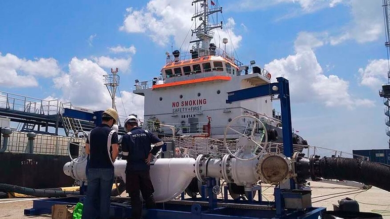 Um skid de comprovação de medidores mestre da Endress+Hauser em frente a um navio de bunker singapurense no porto